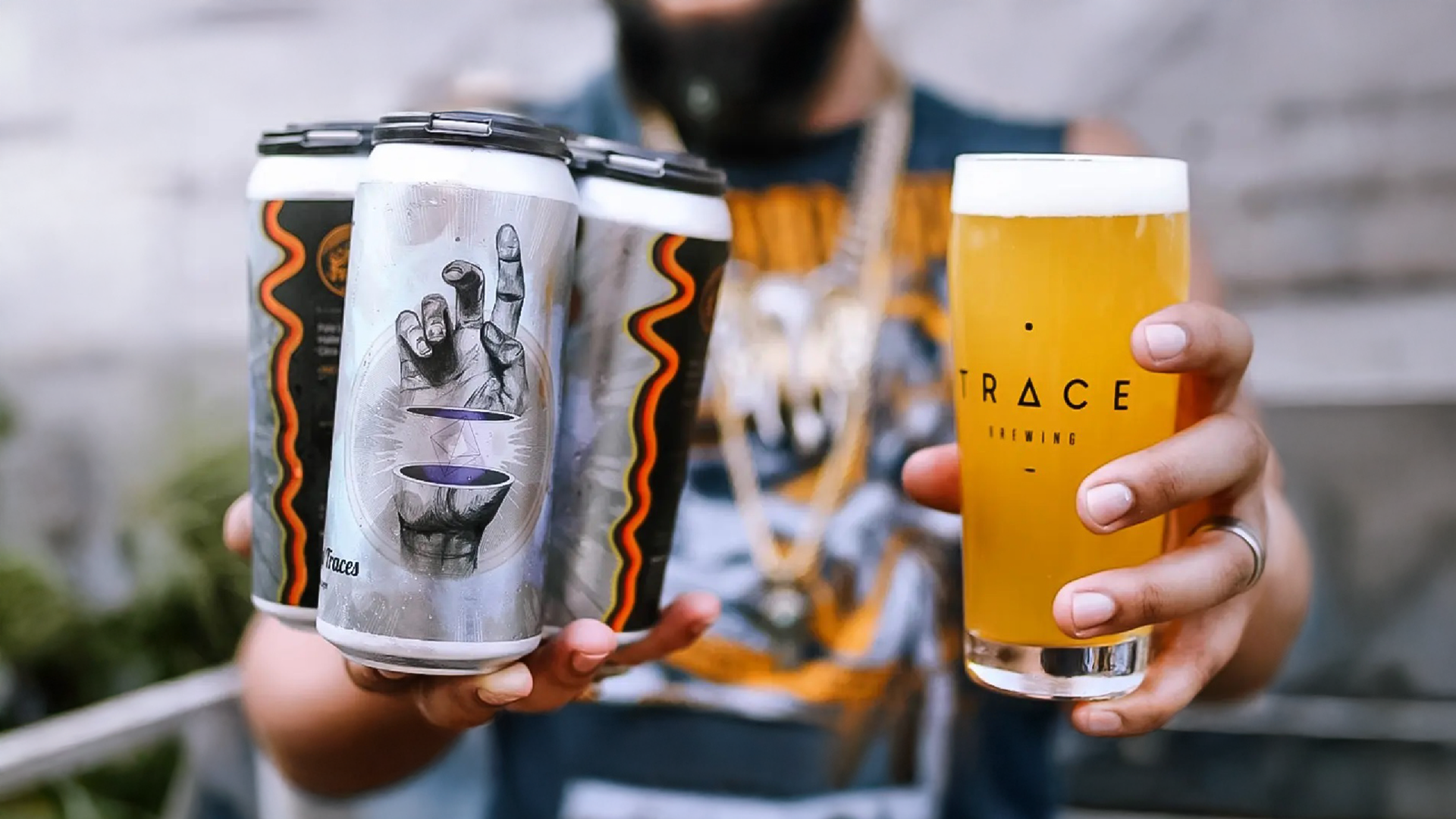An image of a man holding cans and a drink in their hands. the lables of the can have a hand cut in half with a diamond shaped glowing form inside of it.